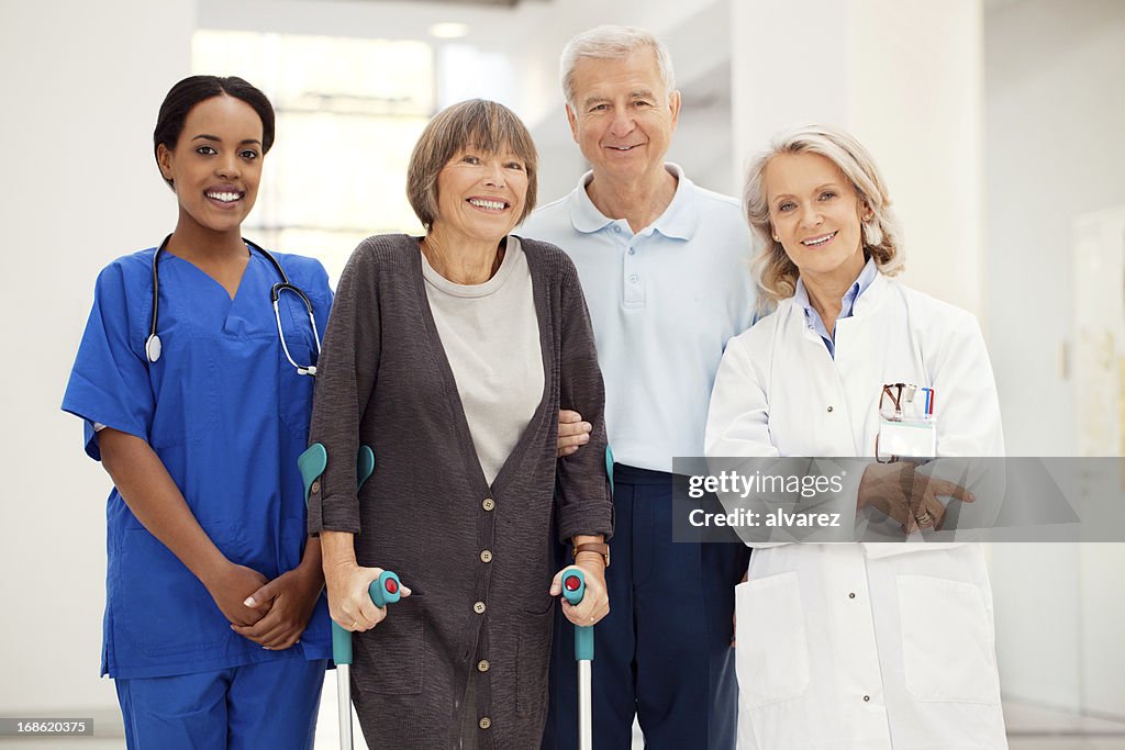 Senior woman with crutches and hospital staff