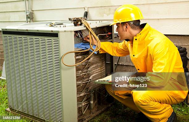 electrician, repairman raincoat working on air conditioning unit outdoors. - ac repair stock pictures, royalty-free photos & images