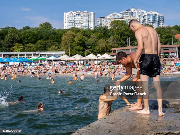 Friends swim and jump into the sea on August 26, 2023 in Odessa, Ukraine. Several beaches in Ukraine's Black Sea city port of Odessa were officially...