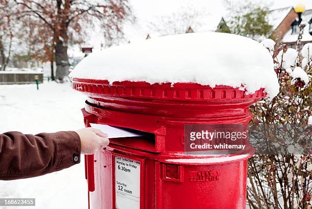 man posting letter in snow-covered british postbox - mail box stock pictures, royalty-free photos & images