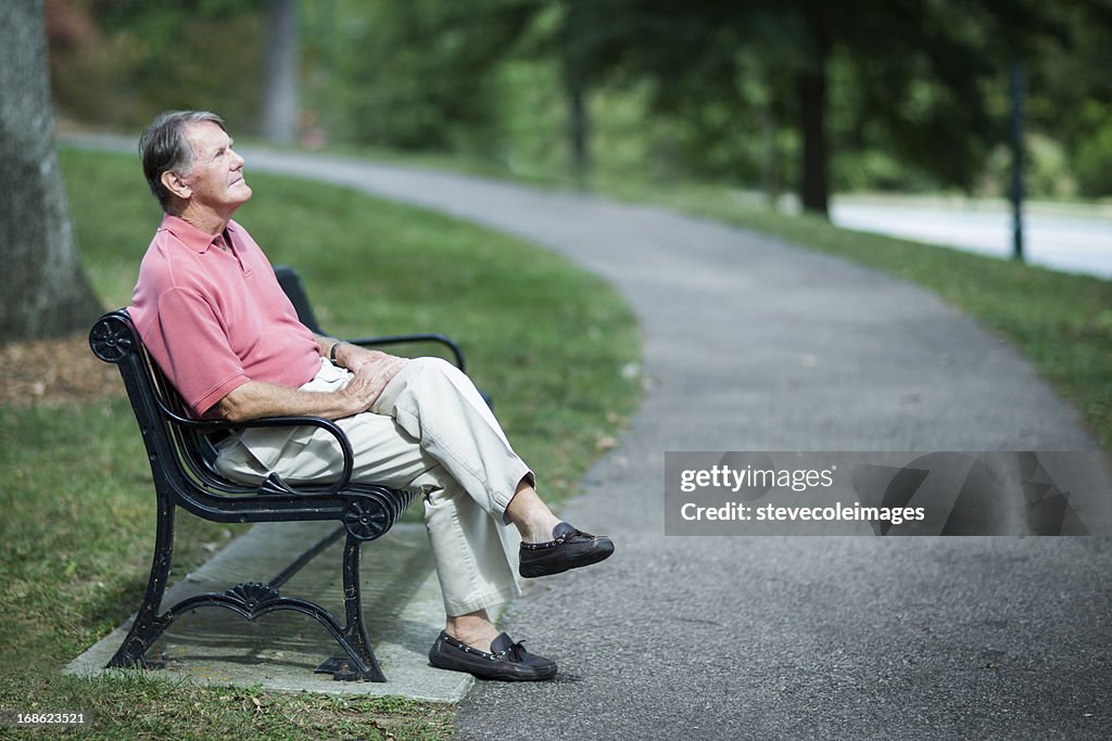 Senior Man Relaxing On Park Bench.