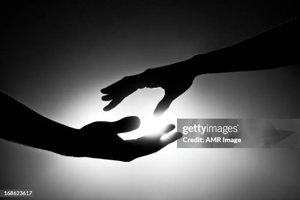 black and white image of two hands reaching out - light at the end of the tunnel stock pictures, royalty-free photos & images