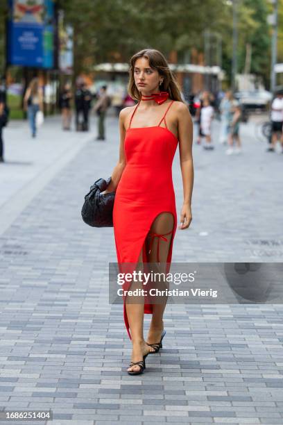 Guest wears red dress, black Bottega Veneta bag, heels outside David Koma during London Fashion Week September 2023 at the on September 16, 2023 in...