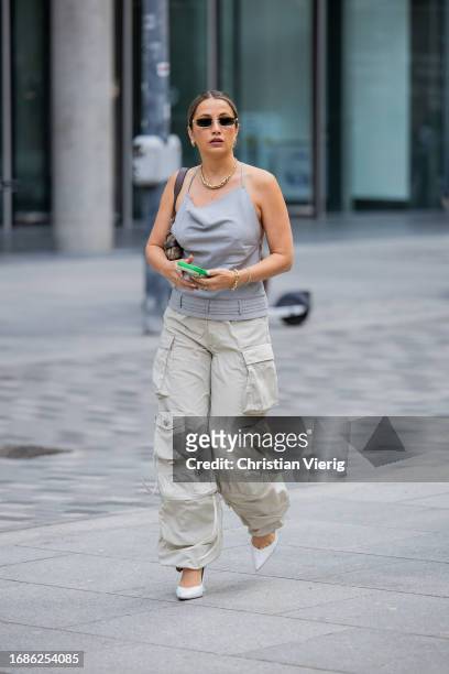 Guest wears grey top, creme white pants with side pockets outside David Koma during London Fashion Week September 2023 at the on September 16, 2023...