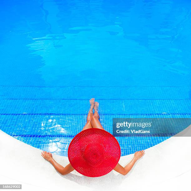 woman relaxing in a resort swimming pool - red hat ladies stock pictures, royalty-free photos & images