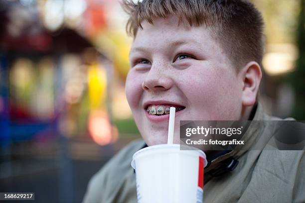 unhealthy eating: redhead overweight teenage boy with soft drink - chubby teenager stockfoto's en -beelden