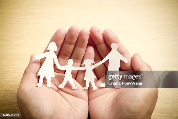 paper family in hands with wooden texture background - protection stock pictures, royalty-free photos & images