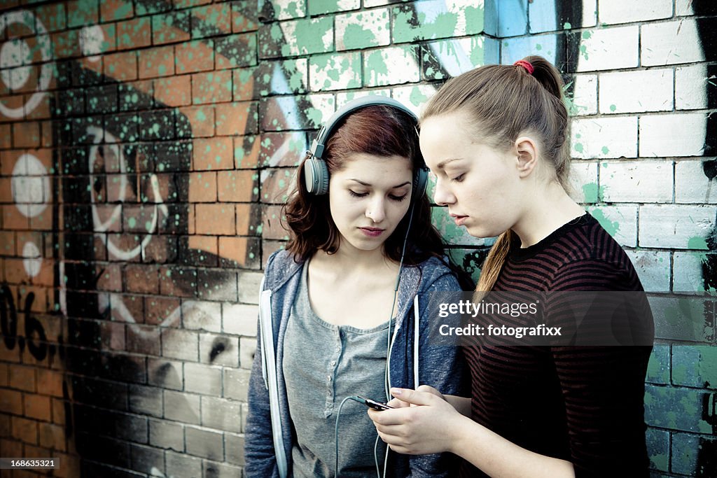 Young women with big headphones looking into a smart phone