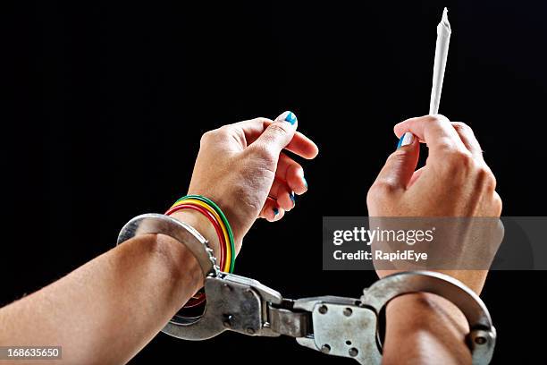 enslaved by drugs handcuffed female hands holding marijuana cigarette - marijuana arrest stock pictures, royalty-free photos & images