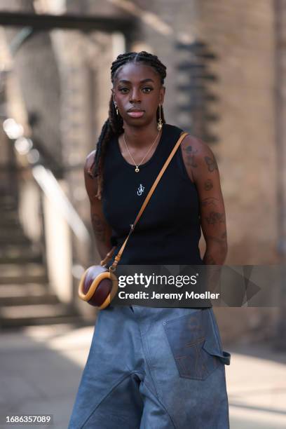 Fashion Show guest was seen wearing black JW anderson top, JW Anderson earrings in yellow gold, a yellow gold chain, blue denim shorts and black...