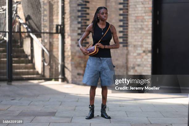 Fashion Show guest was seen wearing black JW anderson top, JW Anderson earrings in yellow gold, a yellow gold chain, blue denim shorts and black...