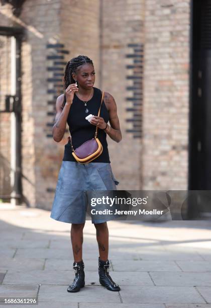 Fashion Show guest was seen wearing black JW anderson top, JW Anderson earrings in yellow gold, a yellow gold chain, blue denim shorts and black...