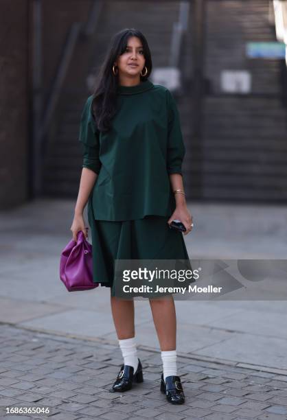 Fashion Show guest was seen wearing black and shiny leather heels, white socks, a purple bag and a skirt and top from Marni in the same green tone...