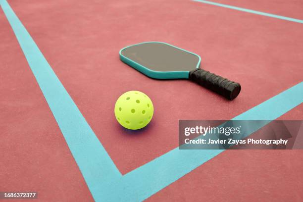 pickleball paddle and ball on red pickle ball court - paddle ball stock pictures, royalty-free photos & images