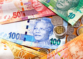 Varied new South African Mandela banknotes with coins