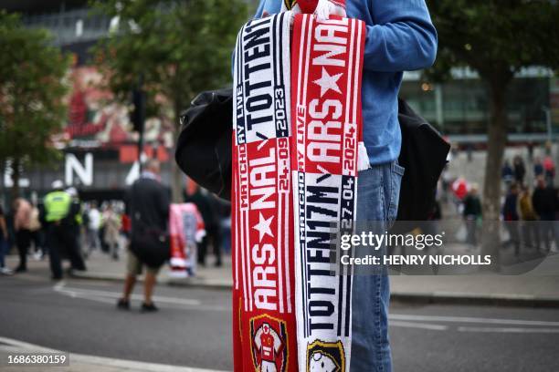 Half and half scarf salesman tries his luck outside the ground ahead of the English Premier League football match between Arsenal and Tottenham...