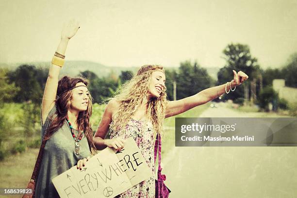 deux femmes faire du stop tenant panneau» partout. - hippies 60s photos et images de collection