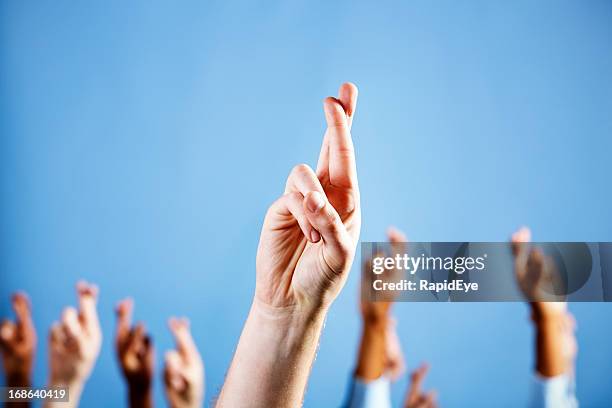 hombre mano con los dedos cruzados superstitiously más en fondo azul - blessing fotografías e imágenes de stock