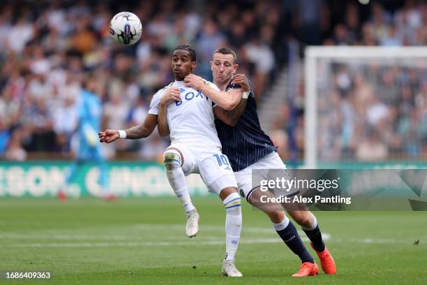 Crysencio Summerville of Leeds United is challenged by Murray Wallace of Millwall during the Sky Bet Championship match between Millwall and Leeds...