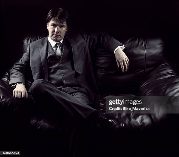 young man sitting on the couch - organised crime stock pictures, royalty-free photos & images