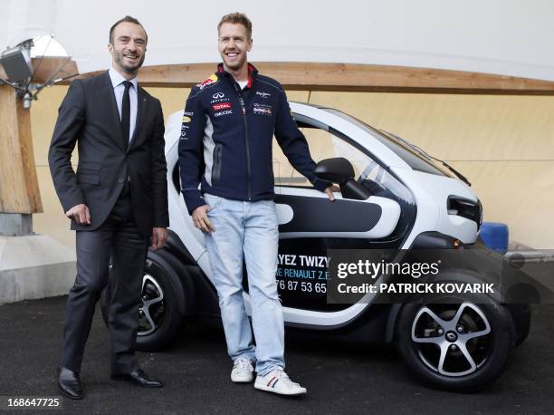 Formula One German triple world champion Sebastian Vettel poses with Renault ZE's director Benoit Treilhou next to a Renault Twizy electric car on...