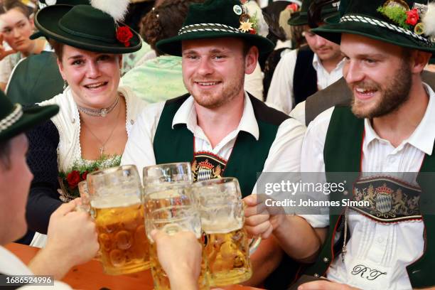 Traditionally dressed participants of the riflemen's parade enjoy drinking beer in the Paulaner tent on the 2nd day of the 2023 Munich Oktoberfest on...