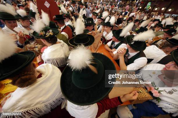 Traditionally dressed participants of the riflemen's parade enjoy drinking beer in the Paulaner tent on the 2nd day of the 2023 Munich Oktoberfest on...