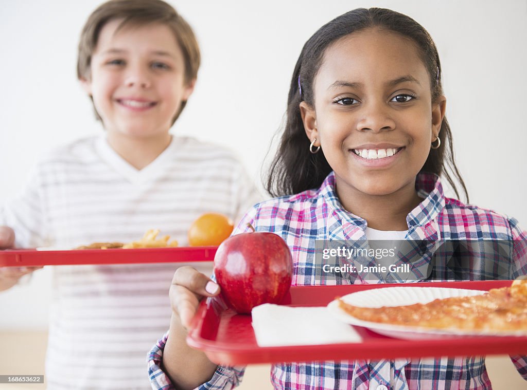 Kids in cafeteria, holding lunch trays