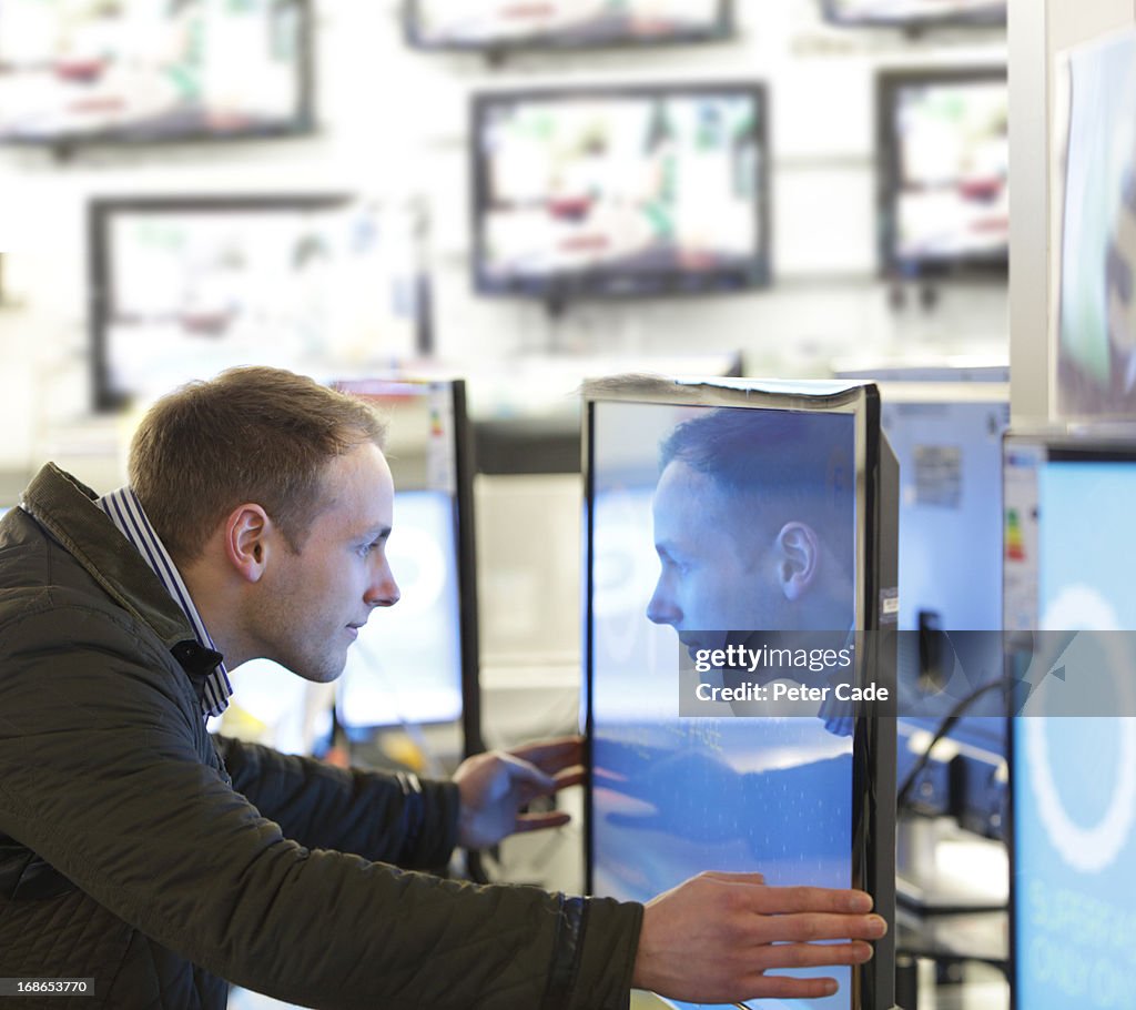 Man looking into television screen in shop