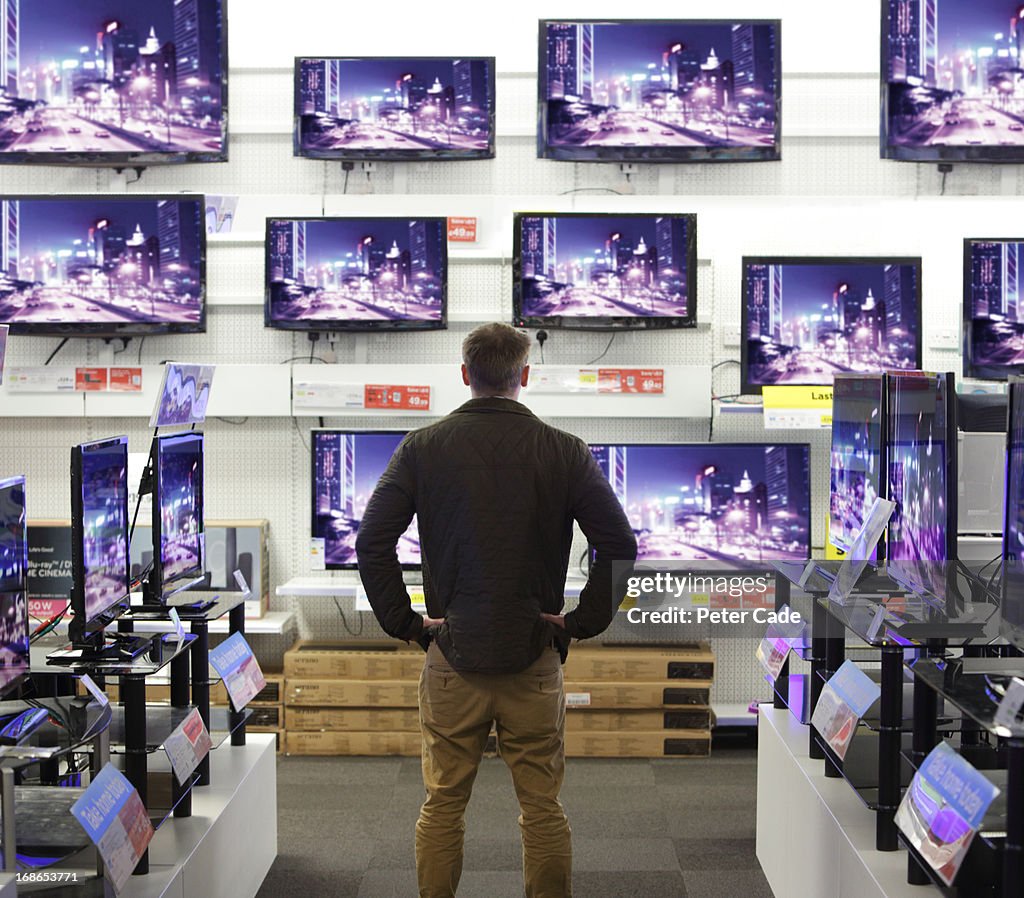 Man stood in shop surrounded by televisions