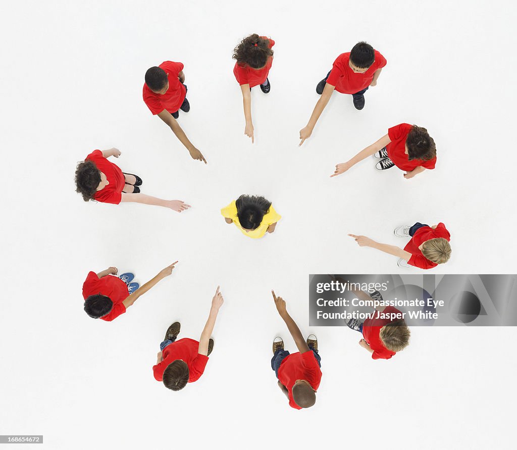 Children standing in circle pointing to centre
