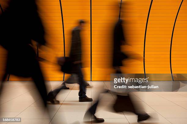 motion blurred commuters in front of modern orange subway tube - perpetual motion stock pictures, royalty-free photos & images