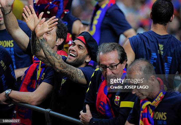 Barcelona's Brazilian defender Dani Alves gestures as he and his teammates parade on a bus through a crowd of celebrating supporters in the streets...
