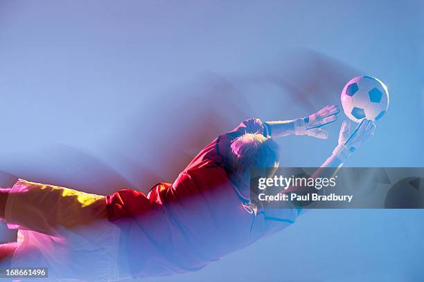 vista turva de lunging bola de jogador de futebol - defesa jogador de futebol imagens e fotografias de stock