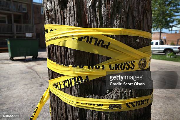 Crime scene tape is wrapped around a power pole near the location where a 20-year-old man died from a gunshot wound to the head and a 15-year-old boy...