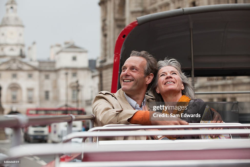 Smiling couple looking up on double decker bus in London