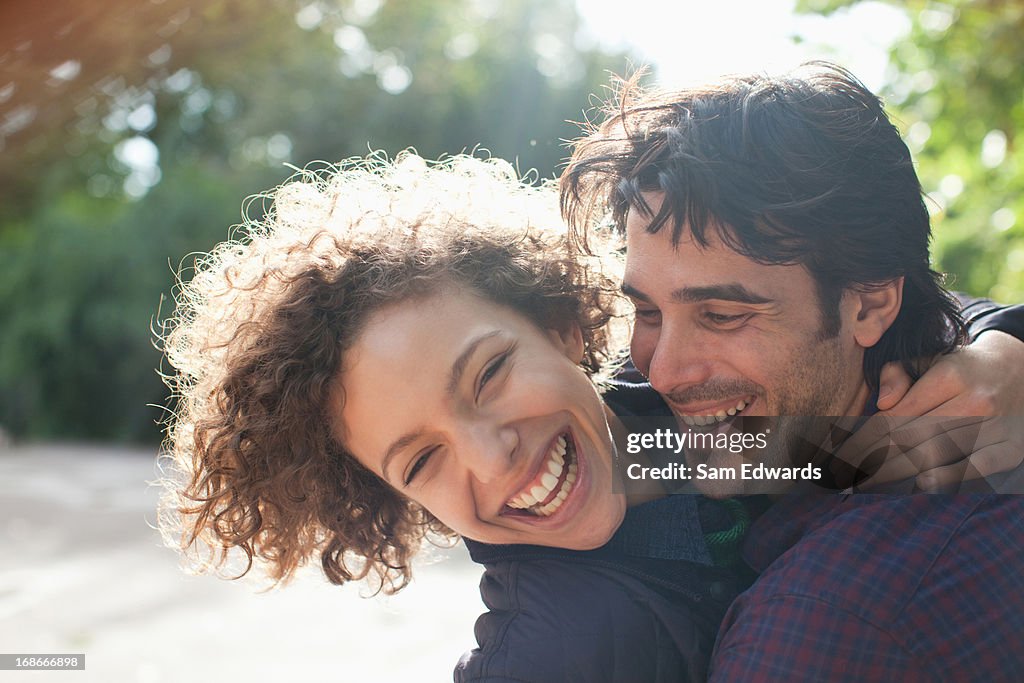 Sun shining behind happy couple hugging
