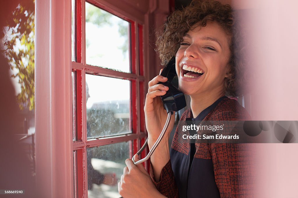 Portrait of smiling woman using telephone booth