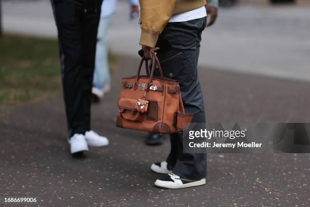 Fashion Week guest is seen wearing grey cargo pants, black/white sneakers and the Cargo Birkin in brown from Hermès during London Fashion Week...
