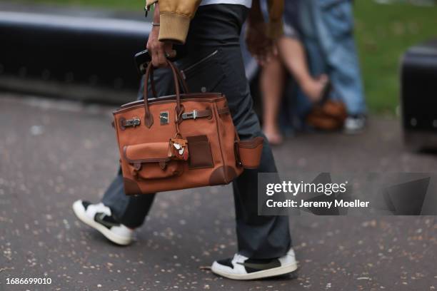 Fashion Week guest is seen wearing grey cargo pants, black/white sneakers and the Cargo Birkin in brown from Hermès during London Fashion Week...