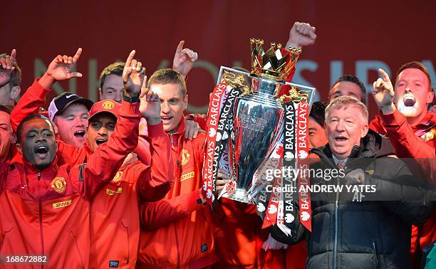 Retiring iconic Manchester United manager Alex Ferguson and his players hold the Premier League trophy outside the town hall in Manchester, north...