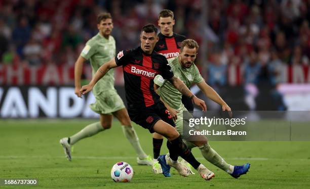 Granit Xhaka of Bayer Leverkusen is challenged by Harry Kane of Bayern Munich during the Bundesliga match between FC Bayern München and Bayer 04...