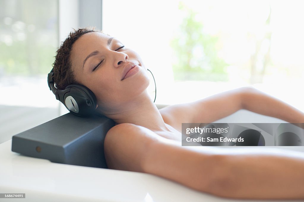 Woman listening music in bathtub