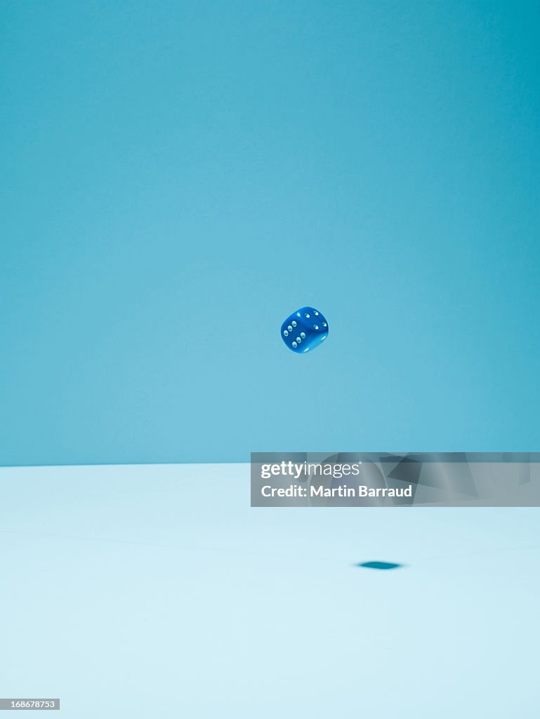 Blue dice in mid-air