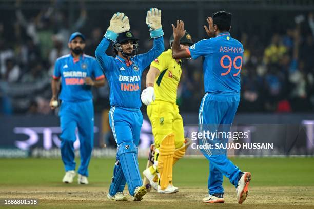 India's Ravichandran Ashwin celebrates with his teammate Ishan Kishan after taking the wicket of Australia's David Warner during the second one-day...