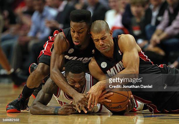 Norris Cole and Shane Battier of the Miami Heat battle for a loose ball with Nate Robinson of the Chicago Bulls in Game Four of the Eastern...