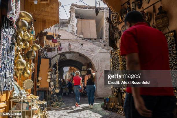 Tourists walk under a building marked with a red 'X,' symbolizing it is unsafe after the earthquake, at the souk on September 17, 2023 in Marrakech,...