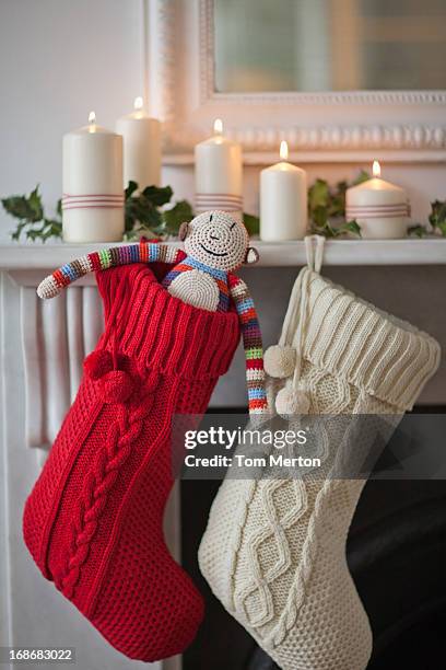 candele luce sulla mensola del camino con calze di natale - calza della befana foto e immagini stock