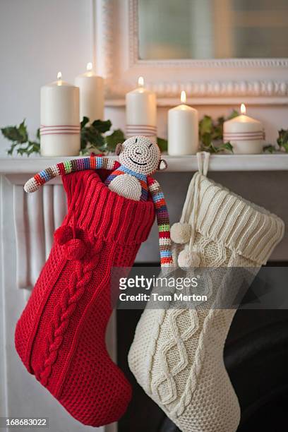 candles lit on mantelpiece with christmas stockings - christmas stocking stock pictures, royalty-free photos & images