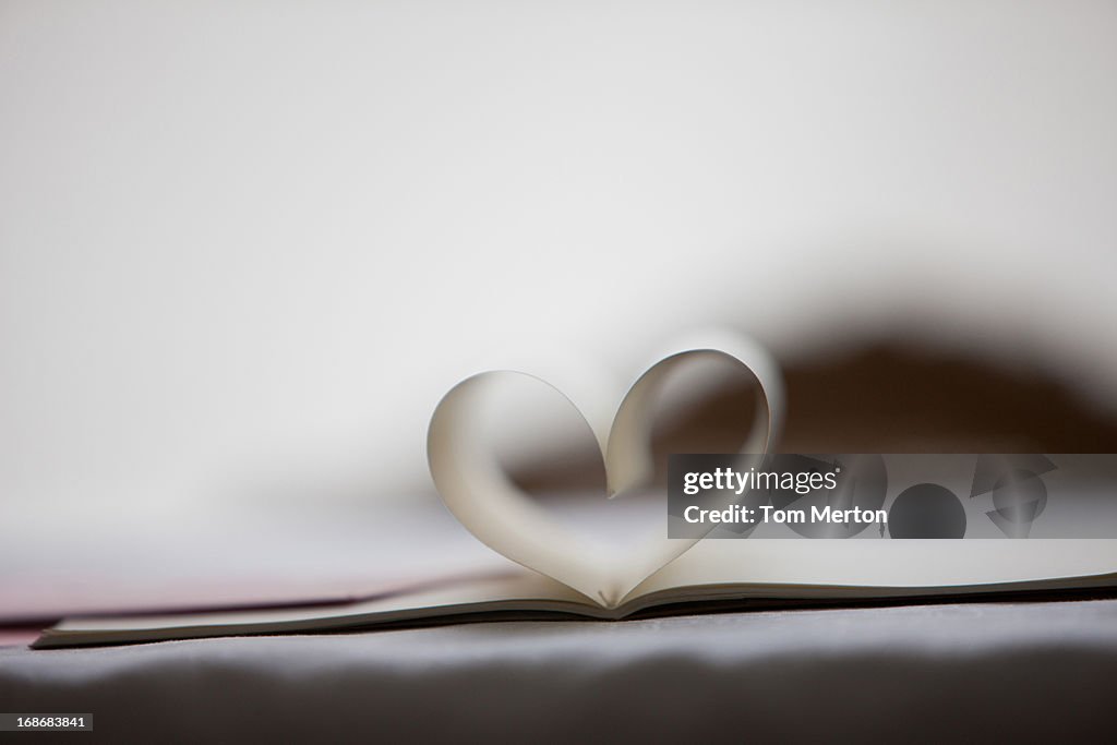 Close up of lipstick kiss on envelope and pages of notebook forming heart-shape